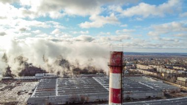 Kışın gün batımında endüstriyel ısıtma istasyonundaki hava manzarası. Doğal gaz yaktıktan sonra dumanlı boruların görüntüsü.