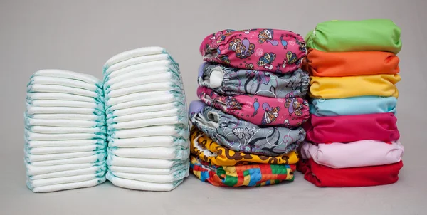 Stacks of disposable diapers and modern cloth diapers — Stock Photo, Image