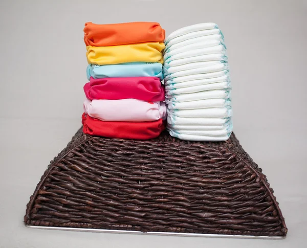 Stacks of disposable diapers and modern cloth diapers — Stock Photo, Image