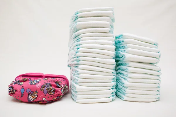 Stacks of disposable diapers and modern cloth diapers — Stock Photo, Image