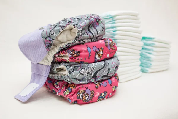 Stacks of disposable diapers and modern cloth diapers — Stock Photo, Image