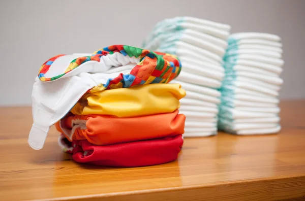 Stacks of disposable diapers and modern cloth diapers — Stock Photo, Image