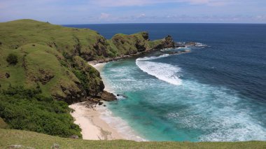 Endonezya 'nın Lombok adasında kar beyazı bir kumsal. Beyaz kum, yeşil tepeler ve Pasifik Okyanusu
