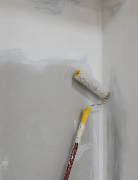 Detalhe da parede inacabada no apartamento e rolo de pintura — Fotografia de Stock
