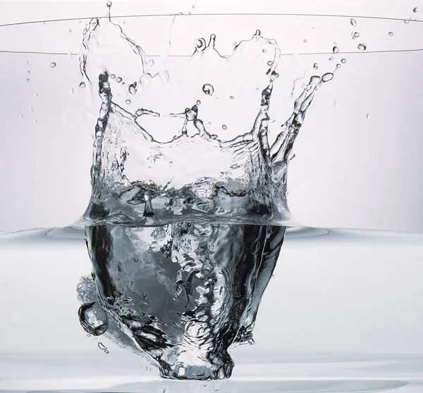 Large ice cube splashing into a glass of wate — Stock Photo, Image