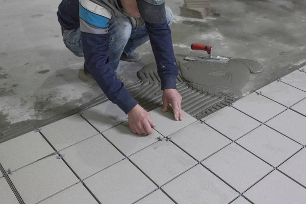 Man placing ceramic floor tile in position over adhesive — Stock Photo, Image