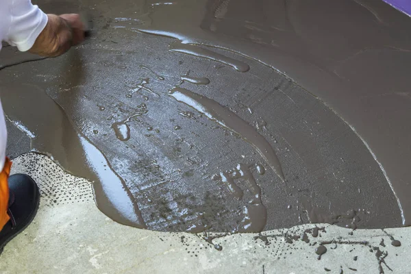 Trabalhador coloca uma mesa de auto-nivelamento com ferramenta no piso de concreto i — Fotografia de Stock