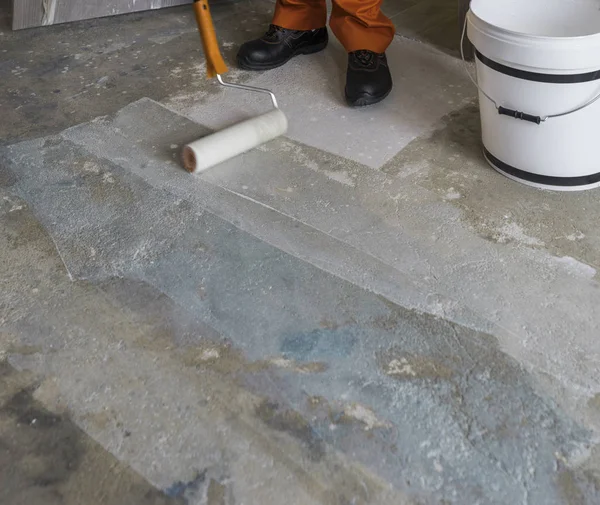 Renovatie van huis. Werknemer legt primer met roller op beton — Stockfoto
