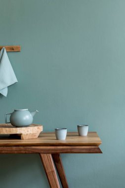 Şık ve minimalist yemek odası. Ahşap masa, fincanlı çaydanlık, meyve tepsisi ve zarif aksesuarlar. Okaliptüs rengi. Kullanmaya hazır. Şablon. Modern ev dekorasyonu. Boşluğu kopyala.