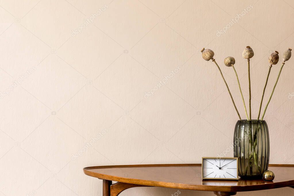 Stylish composition on the design wooden table with gold clock and flowers in vase. Beige background walls. Minimalistic conept of living room. Copy space. Template. 