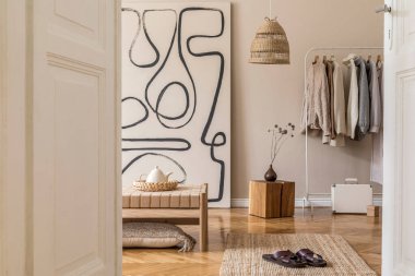 Tasarım şezlongu, ahşap küpü, tabloları, rattan dekorasyonu, elbise askısı ve ev dekorunun doğusundaki zarif aksesuarları olan modern oturma odası kompozisyonu..