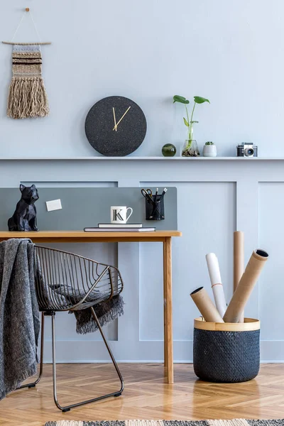 Scandinavian interior design of open space with wooden desk, modern chair, wood paneling with shelf, plant, carpet, office supplies and elegant personal accessories in home decor.