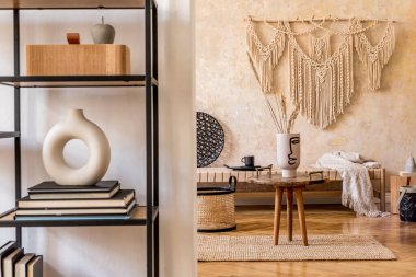 Modern ev dekorunda bej makrome, kahve masası, mobilya, raf, halı ve zarif kişisel aksesuarları olan doğu oturma odasının iç tasarımı.