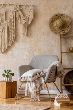 Tasarım koltuğu, güzel makrome, ahşap merdiven, bitki, dekorasyon, halı, kahve masası, kitap ve Wabi Sabi konseptinde zarif kişisel aksesuarları olan şık doğu oturma odası..
