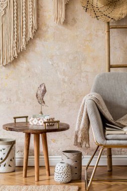 Dizayn koltuğu, sehpa, tahta merdiven, makrome, halı ve modern ev dekorunda zarif aksesuarlarla oturma odasının minimalist kompozisyonu. Wabi sabi duvarı.
