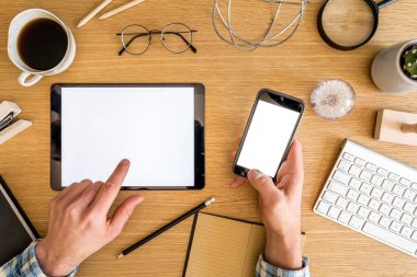 Model tablet ve telefon ekranı, ofis malzemeleri, kahve, telefon, bitkiler ve iş konseptindeki kişisel aksesuarlardan oluşan şık bir ofis kompozisyonu..