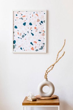 İç tasarım odasının şık kurumuş çiçekleri vazoda, ahşap sehpa, poster çerçevesi, dekorasyon ve modern ev dekorasyonunda kişisel aksesuarlar.. 