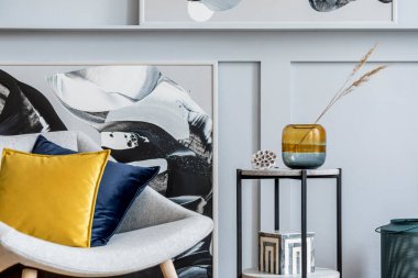 Modern ev dekorunda tasarım gri koltuk, yastıklar, mermer tabure, tablolar, dekorasyon ve zarif kişisel aksesuarları olan şık bir oturma odası..