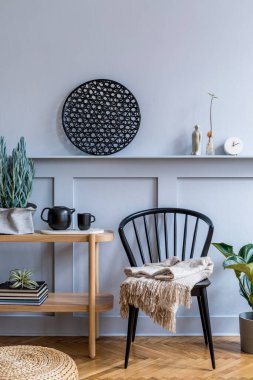 Şık İskandinav oturma odası tasarımı siyah sandalye, ahşap konsol, bitkiler, kitaplar, dekorasyon, çaydanlık, rattan kesesi ve modern ev dekorunda zarif aksesuarlar..