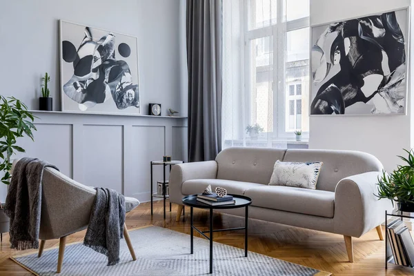 Stylish scandinavian home interior of living room with design gray sofa, armchair, marble stool, black coffee table, modern paintings, decoration, plant and elegant personal accessories in home decor.