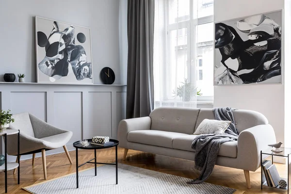 Modern scandinavian home interior of living room with design gray sofa, armchair, marble stool, black coffee table, stylish paintings, decoration and elegant personal accessories in home decor.