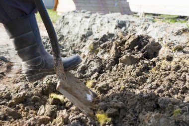 Botların içinde kürekle toprağı kazıyorsun.