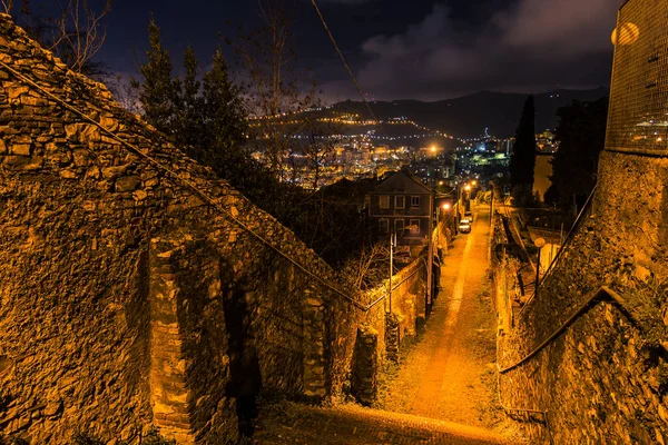 Staircase descending into a narrow street with lanterns in evening Genoa, mountains in the background — Stockfoto