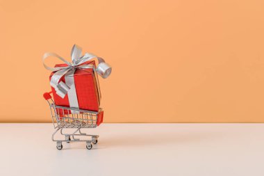 Kırmızı kurdeleli ve alışveriş arabalı bir sürü hediye kutusu.