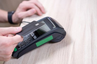 Ödeme için terminali kullanan banka kartı olan bir erkek..