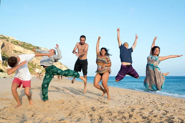 Freunde springen in den Strand — Stockfoto