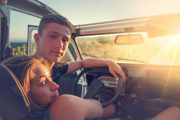 Couple in a car at sunset — Stock Photo, Image