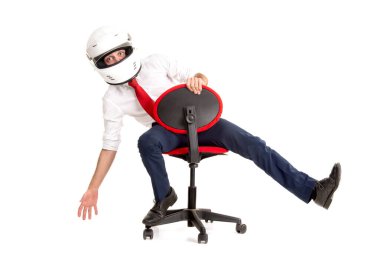 Kafasında kaskla beyaz bir sandalyede yarışan bir iş adamı.