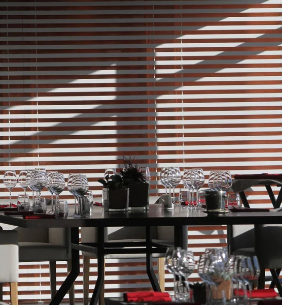 Sluneční světlo osvětluje dřevěný stůl plný prázdných sklenic a bílé svíčky — Stock fotografie