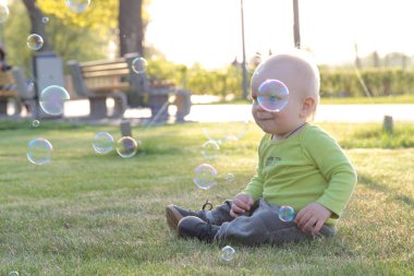 Bir çocuk parkta çim oynuyor.