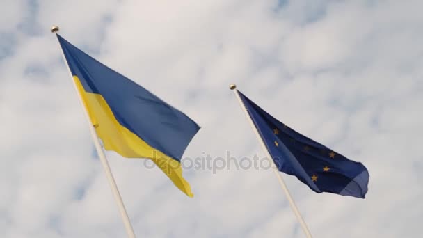 Fahne der Ukraine und Fahne der Europäischen Union flattern vor wolkenverhangenem Himmel. — Stockvideo