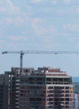 Mavi gökyüzüne karşı inşaat halindeki vinç ve bina