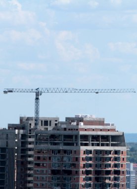 Mavi gökyüzüne karşı inşaat halindeki vinç ve bina