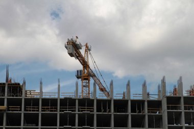 Mavi gökyüzüne karşı inşaat halindeki vinç ve bina.