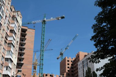 Mavi gökyüzüne karşı inşaat halindeki vinç ve bina.