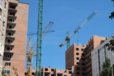 Mavi gökyüzüne karşı inşaat halindeki vinç ve bina.