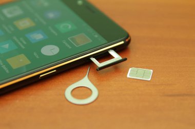 Tahta bir masanın üzerinde yatan siyah smartphone