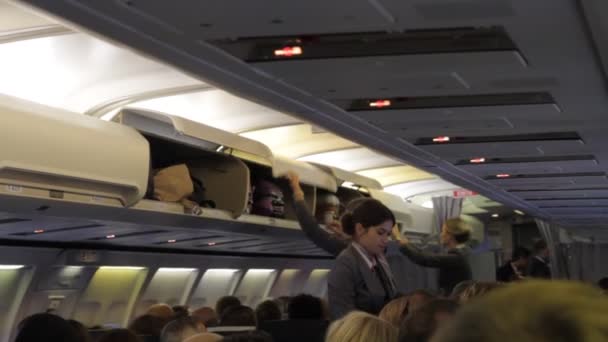 Los pasajeros apilan su equipaje antes del vuelo en la cabina del avión . — Vídeos de Stock