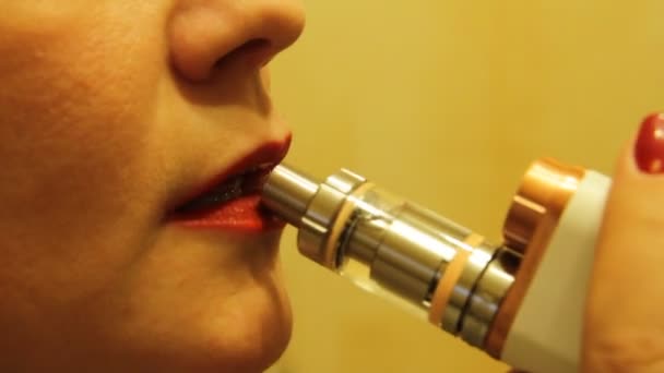 The girl smokes an electronic cigarette vaporizer and releases smoke vapor from her mouth. — Stock Video