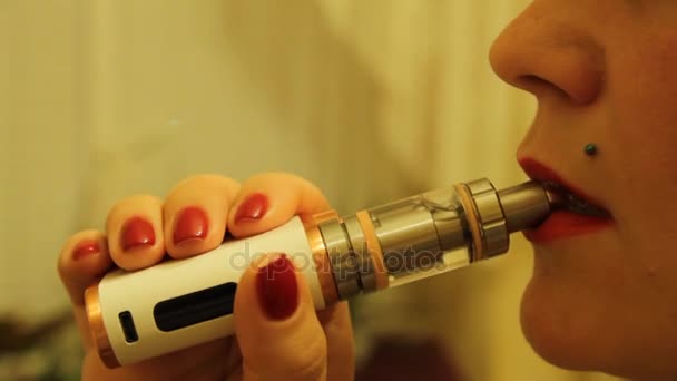 Das Mädchen raucht einen elektronischen Zigarettenverdampfer und gibt Rauchdampf aus ihrem Mund ab. — Stockvideo