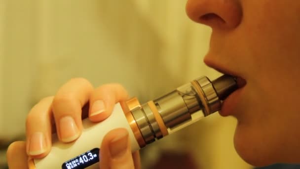 Kız bir elektronik sigara Buharlaştırıcı içiyor ve onun ağzından duman buharı bültenleri. — Stok video