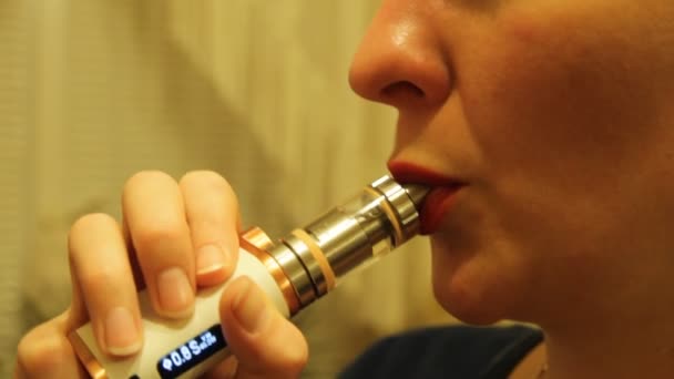 A lány egy elektronikus cigaretta porlasztó dohányzik, és füst gőz kioldja a szájából. — Stock videók