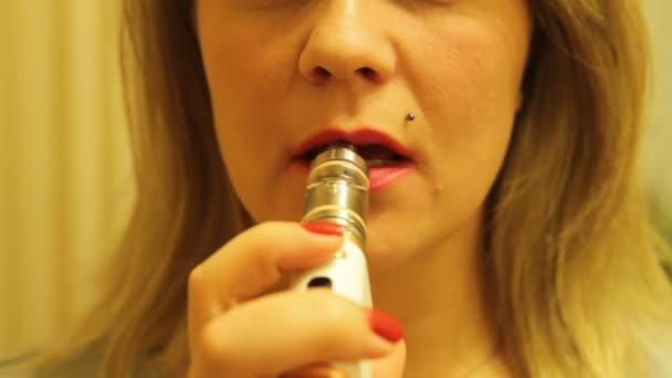 La chica fuma un vaporizador electrónico de cigarrillos y libera vapor de humo de su boca . — Vídeos de Stock