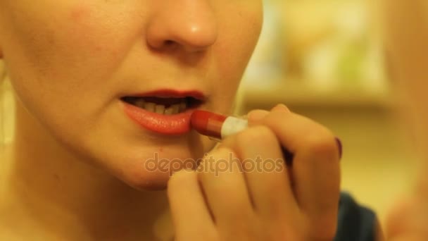 Jonge mooie blonde vrouw schildert haar lippen helder rode kleur lipstick voor een spiegel — Stockvideo