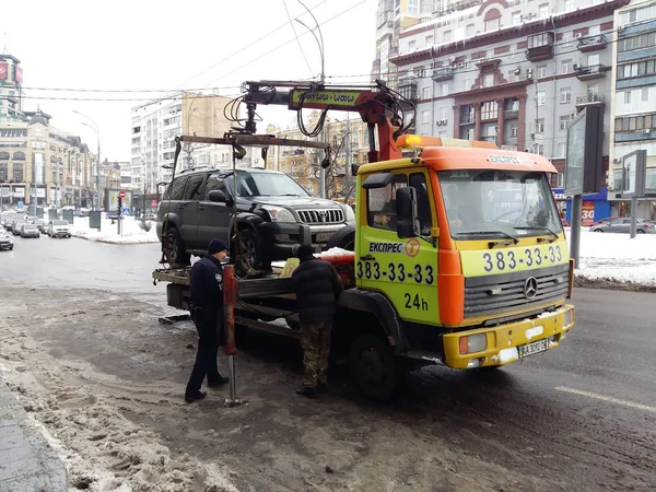 Киев, 6 марта 2018 года, Украина. Сотрудники дорожной полиции на улице, чтобы забрать машину нарушителя на эвакуаторе. Загрузка эвакуатора автомобиля нарушителя правил парковки для эвакуации грузовика — стоковое фото