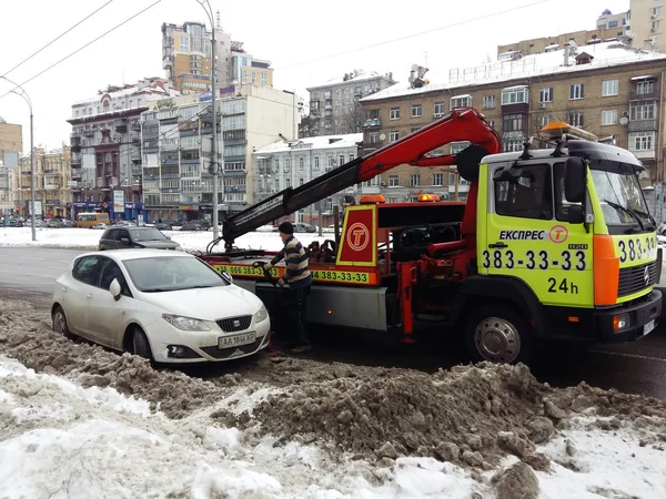 Киев, 6 марта 2018 года, Украина. Сотрудники дорожной полиции на улице, чтобы забрать машину нарушителя на эвакуаторе. Загрузка эвакуатора автомобиля нарушителя правил парковки для эвакуации грузовика — стоковое фото
